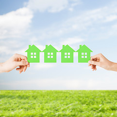 Image showing man and woman hands with many green paper houses