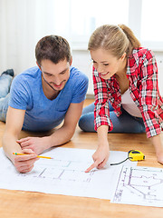 Image showing smiling couple looking at blueprint at home