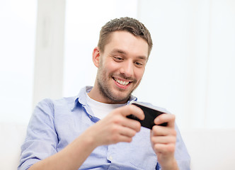 Image showing smiling man with smartphone at home