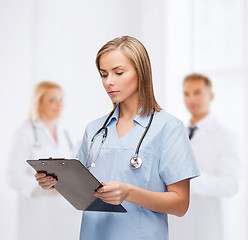 Image showing smiling female doctor or nurse with clipboard