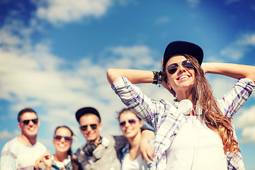 Image showing teenage girl with headphones and friends outside