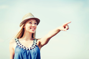 Image showing girl in hat showing direction on the beach