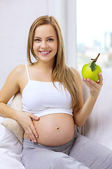 Image showing happy pregnant woman with fresh green apple