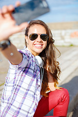 Image showing smiling teenager taking picture with smartphone