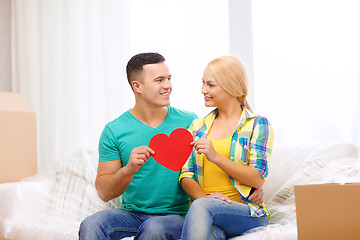 Image showing smiling couple with red heart on sofa in new home
