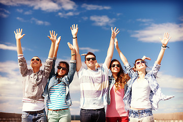 Image showing group of smiling teenagers holding hands up