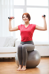 Image showing smiling redhead girl exercising with fitness ball