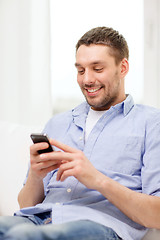 Image showing smiling man with smartphone at home