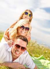 Image showing smiling family in sunglasses lying on blanket