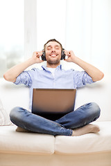 Image showing smiling man with laptop and headphones at home