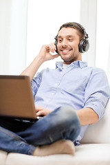 Image showing smiling man with laptop and headphones at home