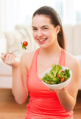 Image showing smiling teenage girl with green salad at home