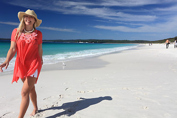 Image showing Happy smiling woman walking along beautiful sandy beach