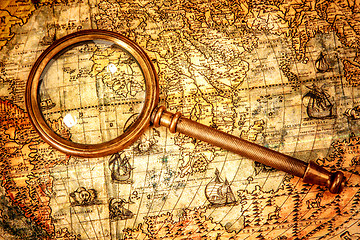 Image showing Vintage magnifying glass lies on an ancient world map