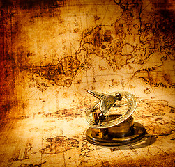 Image showing Vintage compass lies on an ancient world map.