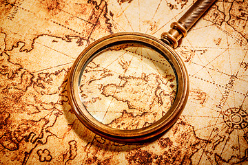 Image showing Vintage magnifying glass lies on an ancient world map