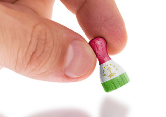 Image showing Hand holding wooden pawn, flag painting, selective focus