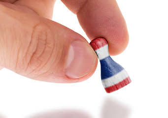 Image showing Hand holding wooden pawn, flag painting, selective focus