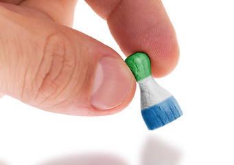 Image showing Hand holding wooden pawn, flag painting, selective focus