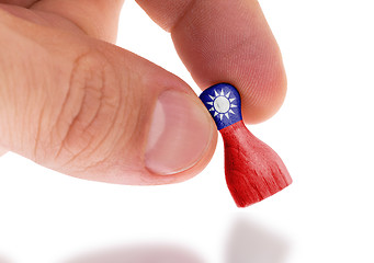 Image showing Hand holding wooden pawn, flag painting, selective focus