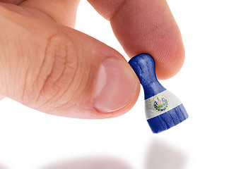 Image showing Hand holding wooden pawn, flag painting, selective focus