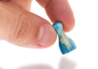 Image showing Hand holding wooden pawn, map painting, selective focus