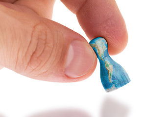 Image showing Hand holding wooden pawn, map painting, selective focus