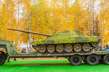 Image showing Tank under camouflage network on truck platform