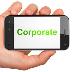 Image showing Hand holding smartphone with word Corporate on display. Generic