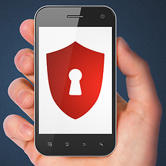 Image showing Hand holding smartphone with shield keyhole