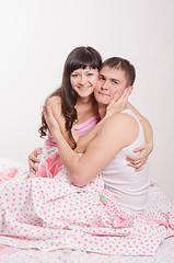 Image showing Young couple embracing, sitting in bed