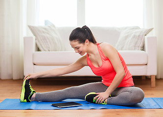 Image showing smiling teenage girl streching on floor at home