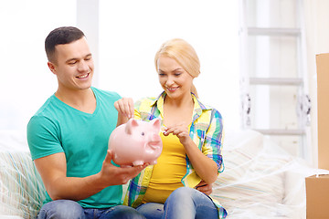 Image showing smiling couple with piggybank in new home