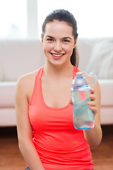 Image showing smiling girl with bottle of water after exercising