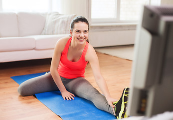 Image showing smiling teenage girl streching on floor at home