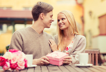 Image showing romantic happy couple with gift in the cafe