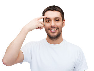 Image showing smiling young handsome man pointing to forehead