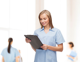 Image showing smiling female doctor or nurse with clipboard