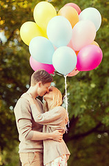 Image showing couple with colorful balloons kissing in the park