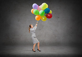 Image showing businesswoman pulling down bunch of balloons