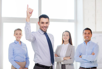 Image showing smiling businessman in office with team on back