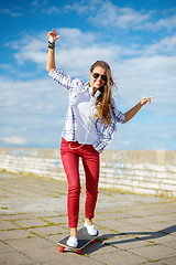 Image showing smiling teenage girl riding skate outside