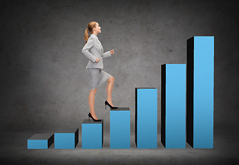 Image showing smiling businesswoman stepping on chart bar