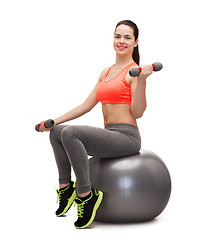 Image showing teenager with dumbbells sitting on fitness ball