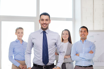 Image showing smiling businessman in office with team on back