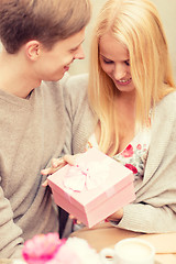 Image showing romantic happy couple with gift in the cafe