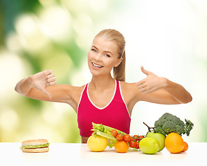 Image showing woman with fruits and hamburger comparing food