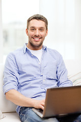 Image showing smiling man working with laptop at home