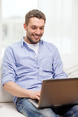 Image showing smiling man working with laptop at home