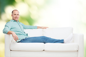 Image showing smiling man lying on sofa